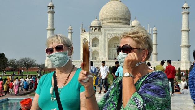Tourists wear a protective mask in wake of coronavirus, as they visit Taj Mahal, in Agra on Wednesday.(ANI photo)