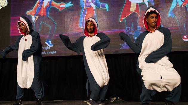 Emiratis Hamad al-Shamsi, left, Rashid al-Qubaisi, center, and Abdullah al-Shamsi, right, perform as the "Squad of Sharks" in a dance-off at the Middle East Film & Comic Con in Dubai, United Arab Emirates, Thursday, March 5, 2020. The Middle East Film & Comic Con began Thursday night in Dubai, a city of skyscrapers and nightclubs suddenly subdued by the outbreak of the new coronavirus across the region. (AP Photo/Jon Gambrell) (AP)