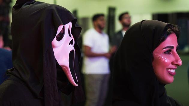 Two Emiratis watch a dance-off at the Middle East Film & Comic Con in Dubai, United Arab Emirates, Thursday, March 5, 2020. The Middle East Film & Comic Con began Thursday night in Dubai, a city of skyscrapers and nightclubs suddenly subdued by the outbreak of the new coronavirus across the region. (AP Photo/Jon Gambrell) (AP)