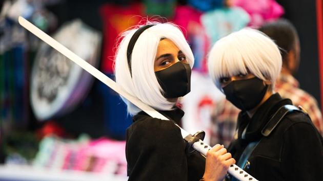 Two women wearing masks dressed as sword-wielding anime characters pose for a photograph at the Middle East Film & Comic Con in Dubai, United Arab Emirates, Thursday, March 5, 2020. The Middle East Film & Comic Con began Thursday night in Dubai, a city of skyscrapers and nightclubs suddenly subdued by the outbreak of the new coronavirus across the region. (AP Photo/Jon Gambrell) (AP)