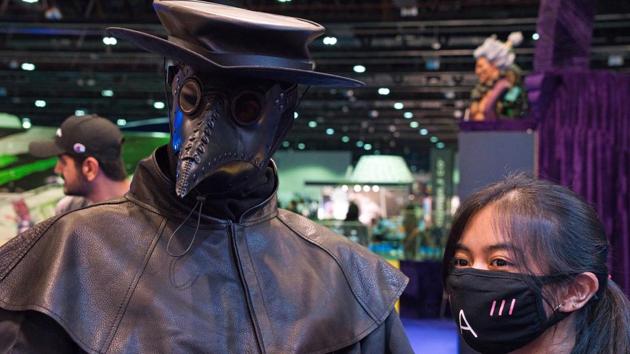 A cosplayer wearing the long, black nose of a plague doctor poses with a woman in a face mask for a photo at the Middle East Film & Comic Con in Dubai, United Arab Emirates, Thursday, March 5, 2020. The Middle East Film & Comic Con began Thursday night in Dubai, a city of skyscrapers and nightclubs suddenly subdued by the outbreak of the new coronavirus across the region. (AP Photo/Jon Gambrell) (AP)