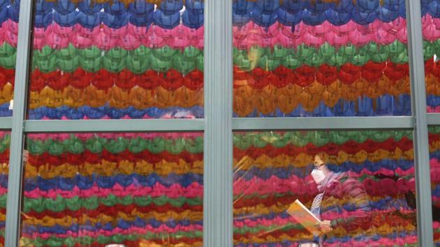 The lantern decorations for the upcoming celebration of Buddha's birthday on April 30 are reflected on the windows as a woman wears a face mask at Jogyesa temple in Seoul, South Korea. Infections of the COVID-19 disease have spread around the globe. (Ahn Young-joon / AP) The lantern decorations for the upcoming celebration of Buddha's birthday on April 30 are reflected on the windows as a woman wears a face mask at Jogyesa temple in Seoul, South Korea. Infections of the COVID-19 disease have spread around the globe. (Ahn Young-joon / AP)