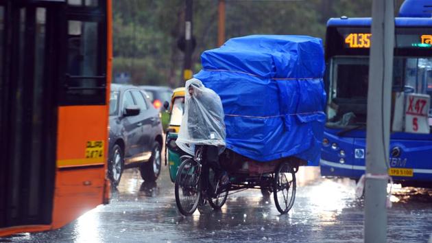 A rickshaw puller covers himself and his cart while riding during rain at ITO in New Delhi. Till 8.30 am on Friday, 20.4 mm rain was recorded over the past 24 hours, the highest 24-hour rainfall in the month of March since 2015 and the second highest in a decade. (Raj K Raj / HT Photo) A rickshaw puller covers himself and his cart while riding during rain at ITO in New Delhi. Till 8.30 am on Friday, 20.4 mm rain was recorded over the past 24 hours, the highest 24-hour rainfall in the month of March since 2015 and the second highest in a decade. (Raj K Raj / HT Photo)