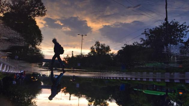An upside down reflection of a person walking on a road after the rain, at Rajghat, in New Delhi, on Friday. The national capital witnessed heavy downpour in the last couple of days, clearing pollutants and brining the mercury down by at least six notches but causing huge traffic jams in the evening peak hours. Consequently, the Air Quality Index (AQI) of the National Capital Region (NCR) also improved. (Sanchit Khanna / HT Photo) An upside down reflection of a person walking on a road after the rain, at Rajghat, in New Delhi, on Friday. The national capital witnessed heavy downpour in the last couple of days, clearing pollutants and brining the mercury down by at least six notches but causing huge traffic jams in the evening peak hours. Consequently, the Air Quality Index (AQI) of the National Capital Region (NCR) also improved. (Sanchit Khanna / HT Photo)