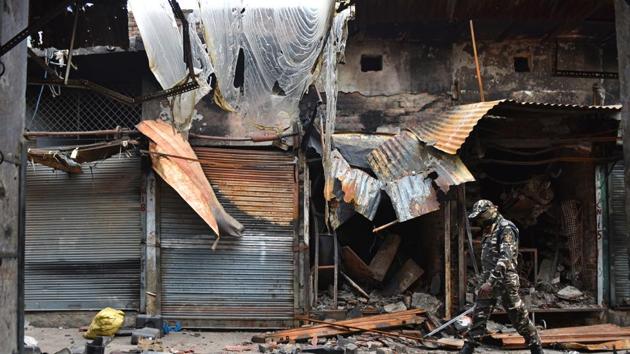 Sashastra Seema Bal (SSB) personnel walk past burnt and damaged shops, which were allegedly set on fire by miscreants during communal violence last week at Gokalpuri market in northeast Delhi on March 4, 2020.(Sanchit Khanna/HT PHOTO)