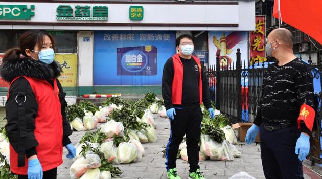 Volunteers wearing face masks stand next to vegetables to be delivered to residents of a residential area in Wuhan, the epicentre of the novel coronavirus outbreak, Hubei province of China.(Reuters Photo)