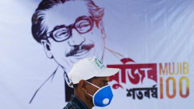 A man wearing a facemask as a preventive measure against coronavirus outbreak, walks past a banner with a painting of Bangladesh’s founder Sheikh Mujibur Rahman in Dhaka on March 8, 2020.(AFP Photo)