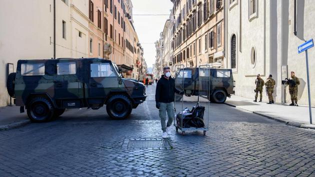 A man wearing a protective mask pulls a cart next to soldiers, who control access to Via del Corso, on Piazza de Popolo in Rome. The lockdown measures came after the latest data showed the coronavirus outbreak continuing to rise, with 9,172 positive cases recorded as of Monday and 463 deaths, the second highest-level in the world after China. (Tiziana Fabi / AFP) A man wearing a protective mask pulls a cart next to soldiers, who control access to Via del Corso, on Piazza de Popolo in Rome. The lockdown measures came after the latest data showed the coronavirus outbreak continuing to rise, with 9,172 positive cases recorded as of Monday and 463 deaths, the second highest-level in the world after China. (Tiziana Fabi / AFP)