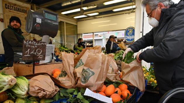 A man wearing a protective mask shops at a fruit and vegetable market in Rome. Shortly after the measures were announced, shoppers in Rome rushed to supermarkets to stock up on food and basic necessities, promoting the government to declare that supplies would be guaranteed and urging people not to panic buy. (Alberto Pizzoli / AFP) A man wearing a protective mask shops at a fruit and vegetable market in Rome. Shortly after the measures were announced, shoppers in Rome rushed to supermarkets to stock up on food and basic necessities, promoting the government to declare that supplies would be guaranteed and urging people not to panic buy. (Alberto Pizzoli / AFP)