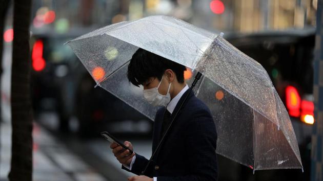 A man, wearing a protective face mask, following an outbreak of the coronavirus disease (COVID-19), uses his phone on a street during a rainfall in Tokyo, Japan. (REUTERS) A man, wearing a protective face mask, following an outbreak of the coronavirus disease (COVID-19), uses his phone on a street during a rainfall in Tokyo, Japan. (REUTERS)