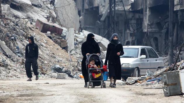 In this file photo taken on March 30, 2018 Civilians walk along a destroyed street in the former rebel-held town of Harasta in Eastern Ghouta, a week after regime forces retook the town from the rebels. (AFP) In this file photo taken on March 30, 2018 Civilians walk along a destroyed street in the former rebel-held town of Harasta in Eastern Ghouta, a week after regime forces retook the town from the rebels. (AFP)
