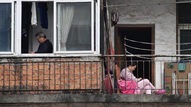 A woman looks at her mobile phone as she sits on a balcony near a man standing by a window at a residential compound. Nearly 50,000 coronavirus cases have been reported in Wuhan, with 2,423 deaths, making it the location hardest-hit by far in an epidemic that has infected more than 119,000 people globally and killed nearly 4,300. (REUTERS) A woman looks at her mobile phone as she sits on a balcony near a man standing by a window at a residential compound. Nearly 50,000 coronavirus cases have been reported in Wuhan, with 2,423 deaths, making it the location hardest-hit by far in an epidemic that has infected more than 119,000 people globally and killed nearly 4,300. (REUTERS)