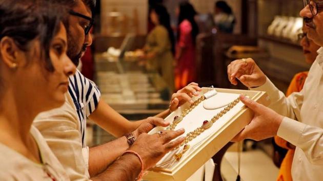 A salesman shows a gold necklace to customers at a jewellery showroom in Ahmedabad, India, in October 2019. (Reuters File Photo) A salesman shows a gold necklace to customers at a jewellery showroom in Ahmedabad, India, in October 2019. (Reuters File Photo)