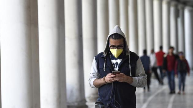 A man checks his phone while wearing a protective mask in New Delhi. The Ministry of Health & Family Welfare released a set of helpline numbers for citizens in case they feel they have developed symptoms related to coronavirus. (Arvind Yadav/HT PHOTO) A man checks his phone while wearing a protective mask in New Delhi. The Ministry of Health & Family Welfare released a set of helpline numbers for citizens in case they feel they have developed symptoms related to coronavirus. (Arvind Yadav/HT PHOTO)