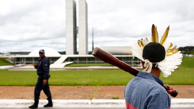 A Brazilian indigenous man and a policeman exchange a glance during a protest demanding the demarcation of indigenous lands, in Brasilia, Brazil. (Sergio LIMA / AFP) A Brazilian indigenous man and a policeman exchange a glance during a protest demanding the demarcation of indigenous lands, in Brasilia, Brazil. (Sergio LIMA / AFP)