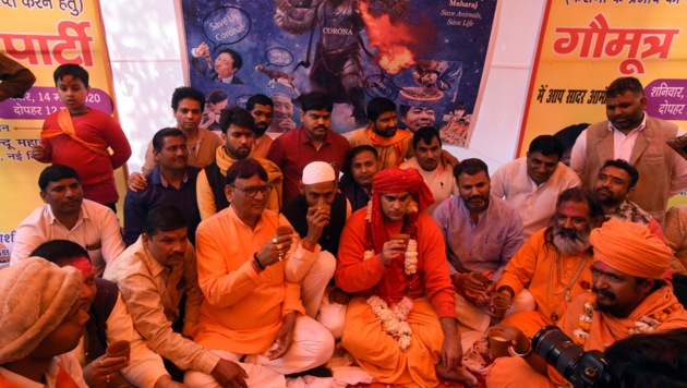 Hindu Mahasabha organisation member drinks with other members and supporters a cup of panchagavya, a traditional Hindu ritual mixture made of cow dung, urine, milk, curd and ghee, as they attend a ‘gaumutra (cow urine) party’ to fight coronavirus in New Delhi.(Photo: Sonu Mehta/ Hindustan Times)