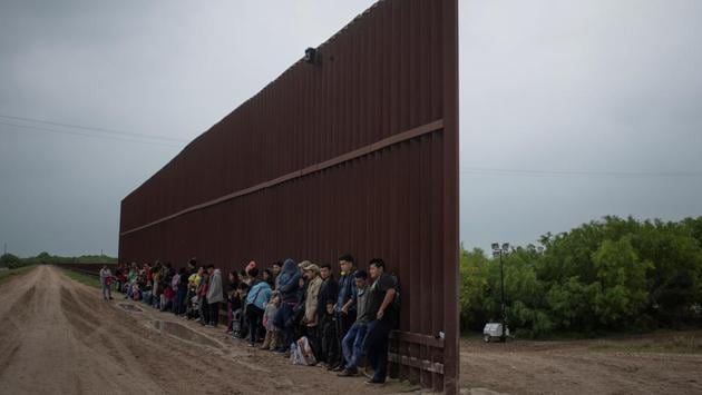 Asylum seeking migrants from Central America line-up along the border wall as they wait to surrender to the US border patrol. Now, once again, agents find they are dealing more with the traditional crossers known as “runners” - economic migrants, mostly young men, looking to enter illegally into the United States in order to work. (Adrees Latif / REUTERS)