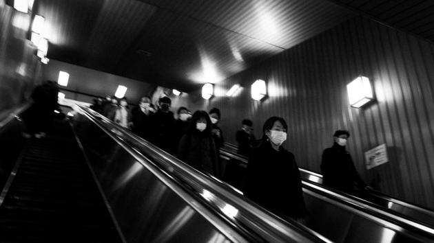 Commuters ride escalators at a train station. The notoriously crowded Tokyo morning rush-hour trains are sparsely populated. Classrooms are eerily empty. Store shelves are bare. (Jae C Hong / AP) Commuters ride escalators at a train station. The notoriously crowded Tokyo morning rush-hour trains are sparsely populated. Classrooms are eerily empty. Store shelves are bare. (Jae C Hong / AP)