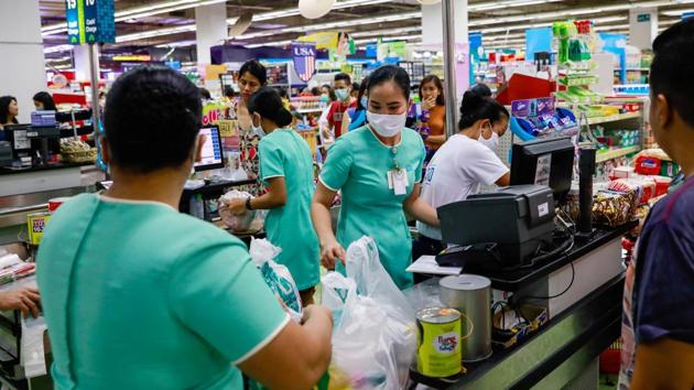A worker wearing a protective face mask picks up items as shoppers queue to buy groceries at a supermarket amid new cases of coronavirus, in Manila, Philippines. (Eloisa Lopez / REUTERS) A worker wearing a protective face mask picks up items as shoppers queue to buy groceries at a supermarket amid new cases of coronavirus, in Manila, Philippines. (Eloisa Lopez / REUTERS)
