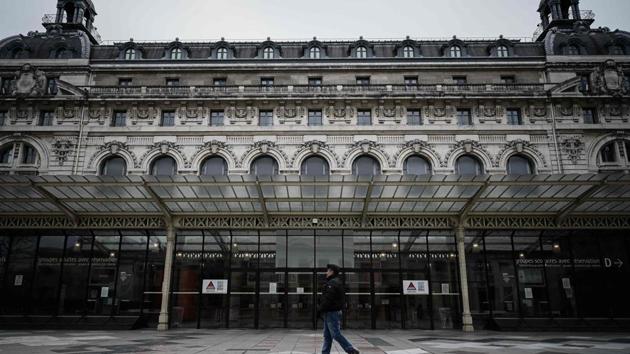 A person walks past the Orsay Museum closed in Paris amid the outbreak of COVID-19, the new coronavirus. All the French schools will be closed until further notice from March 16, the French president announced, calling on those over 70 and the most vulnerable to stay at home, to protect themselves from the infection.  (Philippe LOPEZ / AFP) 