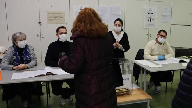 Masked voting volunteers face a woman voting for local elections Sunday March 15, 2020 in Paris. France is holding nationwide elections Sunday to choose all of its mayors and other local leaders despite a crackdown on public gatherings because of the new virus. For most people, the new coronavirus causes only mild or moderate symptoms. For some it can cause more severe illness.(AP)