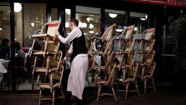 A restaurant employee clears out all the outdoor seats of the eating joint, as France's Prime Minister ordered closure of most of the ‘non-indispensable’ locations, notably cafes, restaurants, cinemas, nightclubs and shops from midnight March 14 due to concerns over the coronavirus (COVID-19), in Paris, France. (Benoit Tessier / REUTERS) 