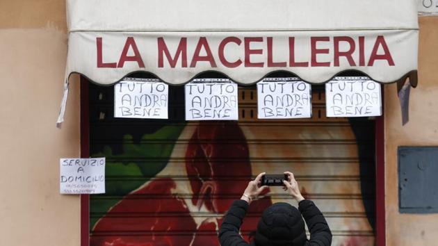Coronavirus outbreak: A woman take photos of notes hanging from a butchery shop and reading in Italian "Everything will be alright", in Rome. (AP) Coronavirus outbreak: A woman take photos of notes hanging from a butchery shop and reading in Italian "Everything will be alright", in Rome. (AP)