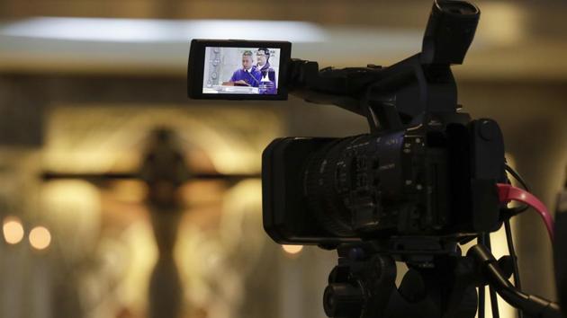 Catholic priest Rymond Ratilla is seen on the viewfinder at a mass that is live video streamed on their Facebook page at an empty Chapel of the Nativity of the Blessed Virgin Mary in Cubao, Quezon city, Philippines, Sunday, March 15, 2020. Mass was suspended at all churches in the capital to avoid large gatherings as part of precautionary measures against the spread of the new coronavirus in this largely Roman Catholic country. For most people, the new coronavirus causes only mild or moderate symptoms. For some, it can cause more severe illness, especially in older adults and people with existing health problems. (AP Photo/Aaron Favila)(AP)