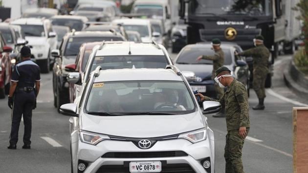 Army troopers use a thermal scanner to check the temperatures of people entering the metropolis at a checkpoint on the outskirts of Quezon city, Philippines.(AP)