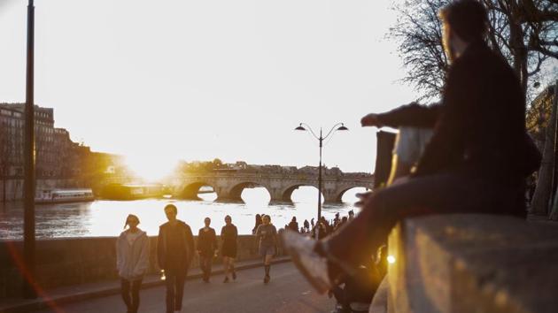 People stroll along the Seine river banks at sunset on Sunday in Paris. (AP Photo) People stroll along the Seine river banks at sunset on Sunday in Paris. (AP Photo)