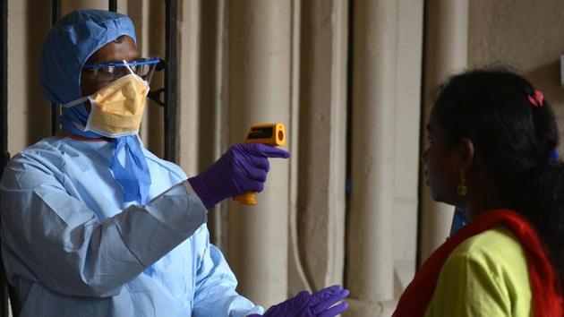 A doctor using a temperature gun to screen people at the Kolkata High Court.(Samir Jana/HT Photo) A doctor using a temperature gun to screen people at the Kolkata High Court.(Samir Jana/HT Photo)
