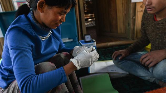 Htan Pi, a community health volunteer with Medical Action Myanmar (MAM) takes a blood sample to test for malaria at her home. Sitting on the porch of her family’s bamboo house that doubles as a clinic, Htan Pi who can administer basic health care insists she is not in competition with her mother -- the village shaman. “People come to me first and only go to my mum if they don’t get better,” she told AFP. (Ye Aung Thu / AFP)