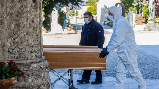 An undertaker unloads a coffin out of a hearse at Bergamo. Italy’s mass quarantining adds emotional stresses to the suffering. Family members can’t travel in ambulances with relatives, and coronavirus units are closed off to anyone not a doctor or a patient. A doctor, not a relative, is often inevitably the last person a dying COVID-19 patient will see. Loved ones can’t even approach coffins for fear of catching the virus. (Piero Cruciatti / AFP) An undertaker unloads a coffin out of a hearse at Bergamo. Italy’s mass quarantining adds emotional stresses to the suffering. Family members can’t travel in ambulances with relatives, and coronavirus units are closed off to anyone not a doctor or a patient. A doctor, not a relative, is often inevitably the last person a dying COVID-19 patient will see. Loved ones can’t even approach coffins for fear of catching the virus. (Piero Cruciatti / AFP)
