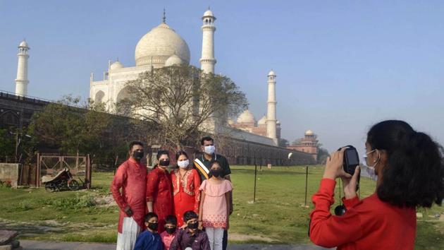 Vistors wearing masks pose for a photograph in the backdrop of the Taj Mahal, a principal tourist site that has also been closed in Agra. ASI data reported the number of foreign tourists fell down to a mere 1,274 on Sunday. In comparison, on any normal day, there are more than 20,000 to 25,000 visitors at the Taj Mahal. (PTI)