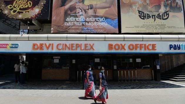Cineplex staff wearing face masks walk past the entrance of the Devi Cineplex closed amid concerns over the spread of the COVID-19 novel coronavirus, in Chennai. Educational institutes, cinema halls and weekly markets have been suspended for various durations across several states in the country, (Arun Sankar / AFP)