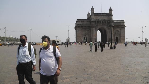 Two men wearing masks walk past the Gateway of India in Mumbai. The financial hub of Mumbai has ordered offices providing non-essential services to keep half their staff at home in increased measures to curb the coronavirus in South Asia. (Rafiq Maqbool / AP)