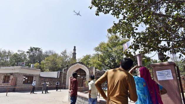 Visitors look at the Qutub Minar from outside after the ASI order. Conceding the effect of coronavirus on the Indian tourism industry in an interview to IANS, Patel claimed that the loss to industry stakeholders was evident but stressed that safety is of utmost importance. (Sanjeev Verma / HT Photo)