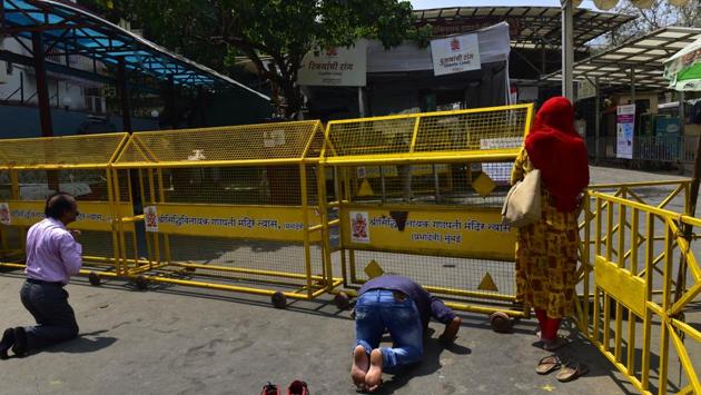 Devotees offer prayers outside the barricaded Siddhivinayak Temple. Along with the Siddhivinayak Temple, dozens of other monuments and museums including the Ajanta and Ellora caves and religious sites were closed. The curbs in Mumbai came just days after the city shut down schools, cinemas, malls and gyms, and also banned mass gatherings. (Anshuman Poyrekar / HT Photo)