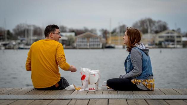 Cameron Shaver and Callie Johnson practice social distancing to prevent the spread of coronavirus disease (COVID-19) as they enjoy dinner at City Dock in Annapolis, U.S., March 18, 2020. REUTERS/Mary F. Calvert(REUTERS)