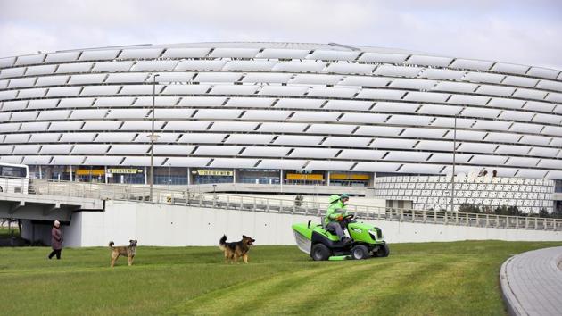 A worker rides a tractor as he mows a lawn in front of the Olympic stadium, where UEFA planned to host four UEFA Euro 2020 matches (AP) A worker rides a tractor as he mows a lawn in front of the Olympic stadium, where UEFA planned to host four UEFA Euro 2020 matches (AP)