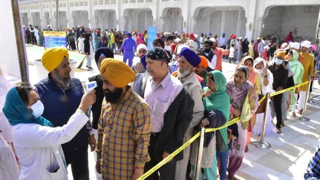 A medic wearing a face mask screens devotees at the main entrance of the Golden Temple.(Sameer Sehgal/Hindustan Times)