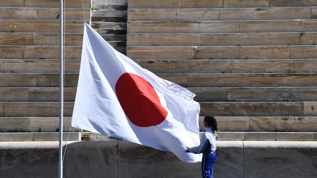 An athlete adjusts the Japanese flag during the Olympic flame handover ceremony. (AP) An athlete adjusts the Japanese flag during the Olympic flame handover ceremony. (AP)