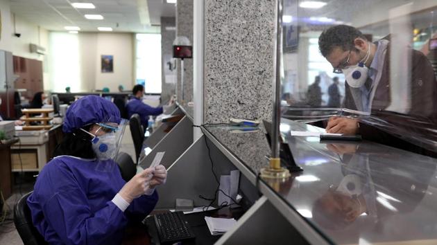 A bank worker and a client wear protective face masks at a bank, following the outbreak of coronavirus, in Tehran, Iran March 17, 2020. (VIA REUTERS)