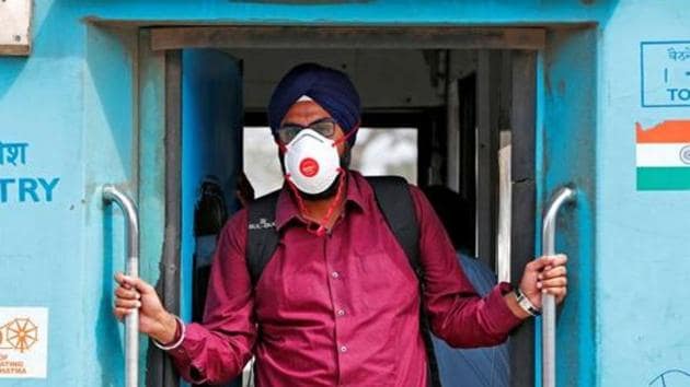 A man wearing a mask as a precaution against the spread of coronavirus stands onboard a train at a railway station in New Delhi.(REUTERS PHOTO.)