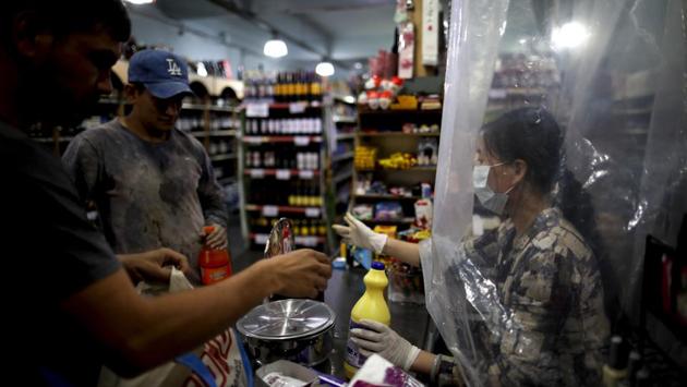 A supermarket cashier waits for costumers behind a makeshift plastic curtain as a precaution against the spread of the new coronavirus in Buenos Aires, Argentina. (Natacha Pisarenko / AP) A supermarket cashier waits for costumers behind a makeshift plastic curtain as a precaution against the spread of the new coronavirus in Buenos Aires, Argentina. (Natacha Pisarenko / AP)