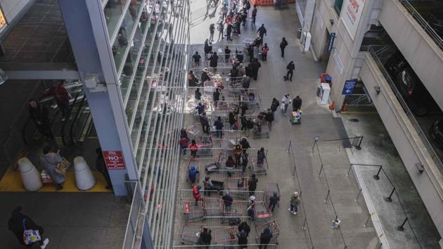 Customers queue with shopping carts outside a local retail store in New York. Whether acting under government orders or following basic public health advice, people are putting distance between themselves to keep the coronavirus away. (Yuki Iwamura / AP) Customers queue with shopping carts outside a local retail store in New York. Whether acting under government orders or following basic public health advice, people are putting distance between themselves to keep the coronavirus away. (Yuki Iwamura / AP)