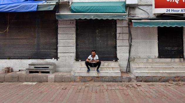 A man sits next to closed shops at Sarojini Nagar market, in New Delhi, India, on Saturday, March 21, 2020.(Amal KS/HT PHOTO)