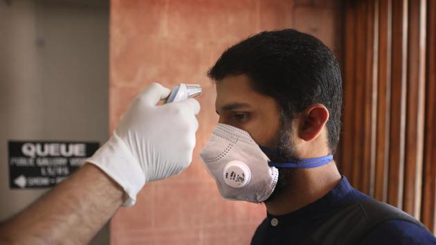 Coronavirus in India: A security official checks the temperature of a visitor as a precaution against the new coronavirus at the Parliament House in New Delhi.(AP) Coronavirus in India: A security official checks the temperature of a visitor as a precaution against the new coronavirus at the Parliament House in New Delhi.(AP)