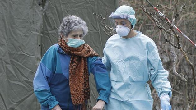 An elderly patient is helped by a doctor at one of the emergency structures that were set up to ease procedures at the Brescia hospital, northern Italy.(AP)
