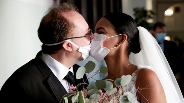 Newlyweds Diego Fernandes and Deni Salgado kiss through protective face masks at a wedding ceremony with only witnesses and no guests, as public gatherings are banned as part of Italy’s lockdown measures to prevent the spread of coronavirus disease in Naples, Italy. (Ciro De Luca / REUTERS)